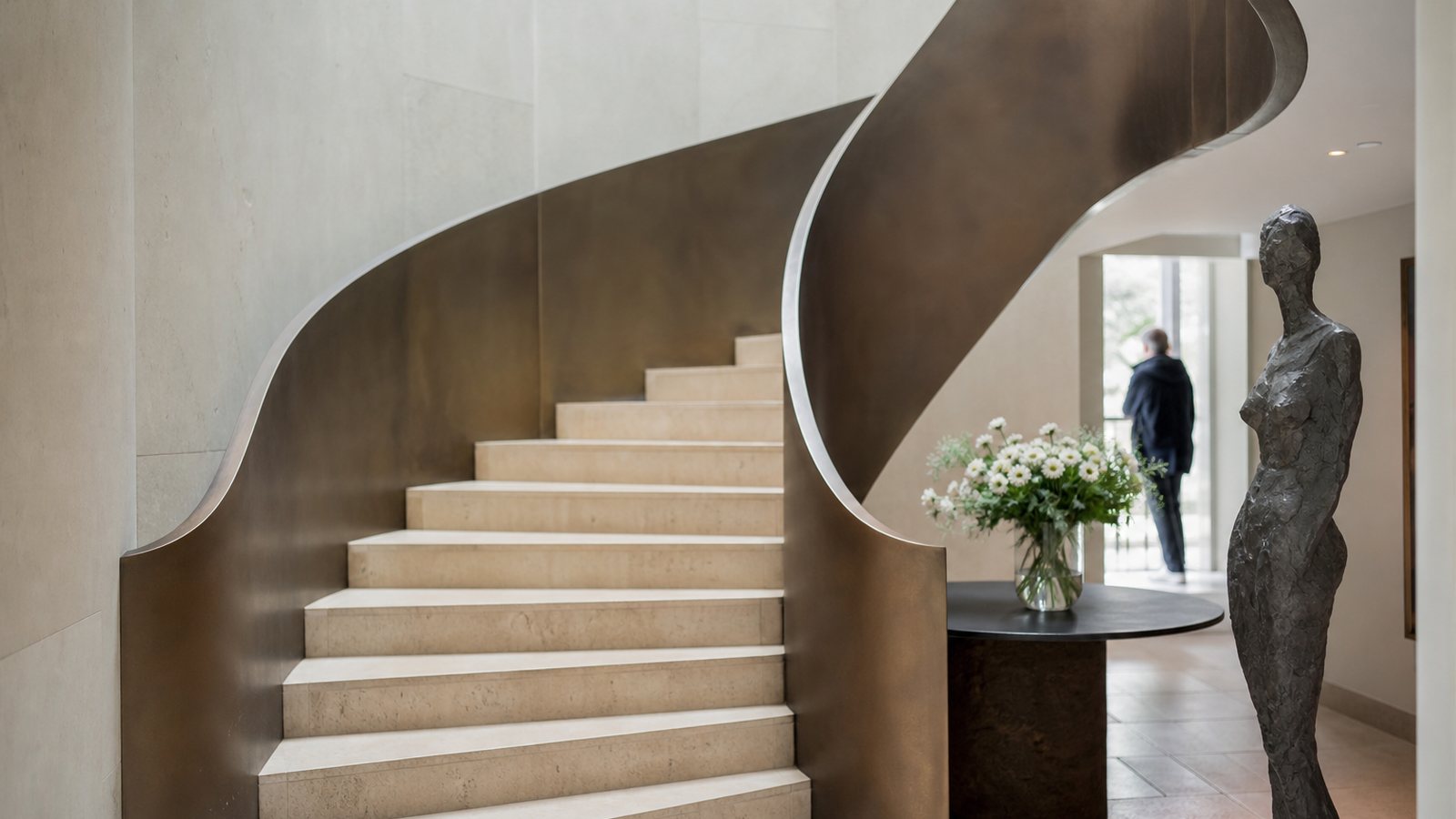 Escalier design sur mesure en acier et bois structurant l'entree d'une maison contemporaine lumineuse